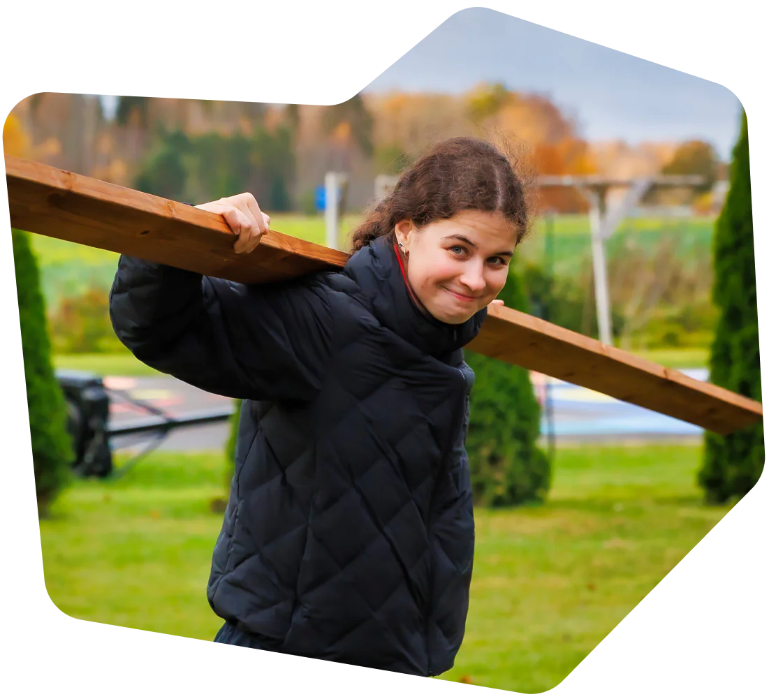 A Twilion Carrying a Wooden Plank Outdoors A Twilion Carrying a Wooden Plank Outdoors
