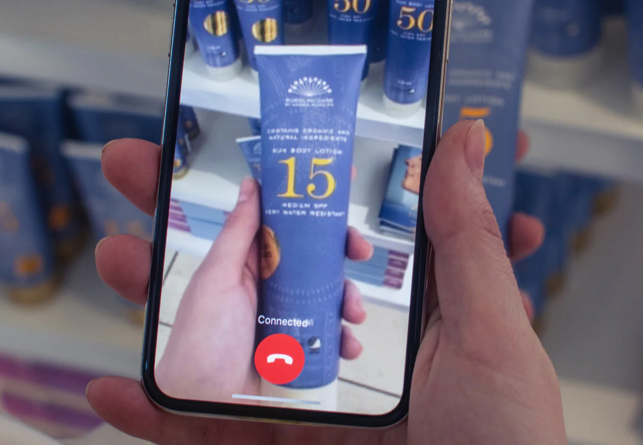 An image of a smart phone with Be My Eyes application connecting a helper to the user to identify a bottle of sunscreen